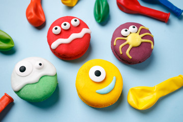 Heloween dessert: funny monsters made of biscuits macaroon with icing and candy eyes close-up on...