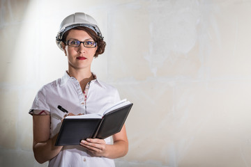 Cute young woman in white construction protection building helmet in unfinished apartment © keleny