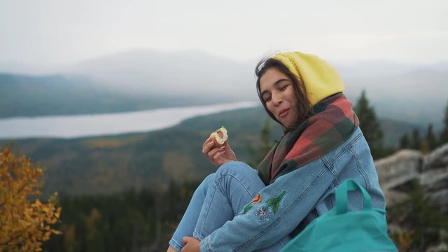 Girl eating hot dog on top of mountain.