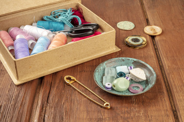 Fototapeta na wymiar A photo of a sewing box with threads and scissors, with a vintage pin, beads and buttons, and copy space