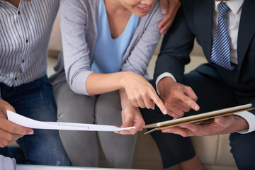 Cropped image of estate agent showing blueprints to couple at meeting