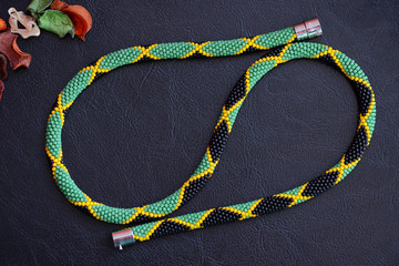Bead crochet necklace in Jamaican style on a dark background close up