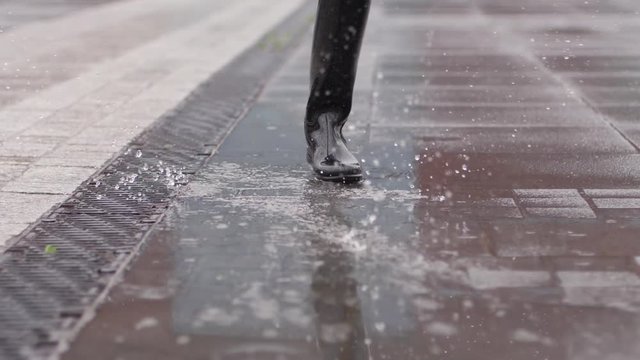 Good mood for rainy weather woman in rubber boots with high bootleg in puddle makes splash