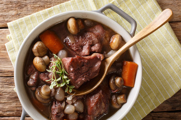 Traditional French food: Coq au vin cock with wine and vegetables, thyme close-up in a pot. horizontal top view from above