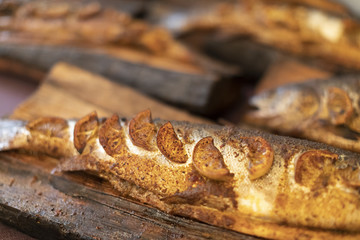 Smoked fish on a wood plank on a purple tablecloth