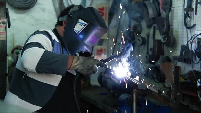 Male Professional Welder in Welding Helmet working at Workshop. 