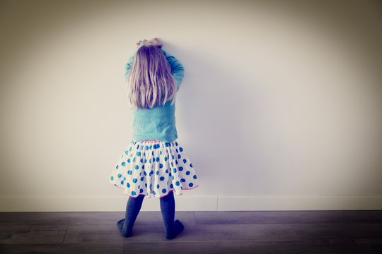 Little girl standing up against a wall