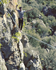 Highliner on a rope. Highline on a background of mountains. Extreme sport on the nature. Balancing on the sling. Equilibrium at altitude.