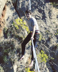 Highliner on a rope. Highline on a background of mountains. Extreme sport on the nature. Balancing on the sling. Equilibrium at altitude.