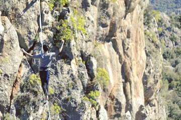 Highliner on a rope. Highline on a background of mountains. Extreme sport on the nature. Balancing on the sling. Equilibrium at altitude.