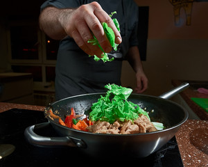 Caucasian chief cook cooking on the wok pan with flambe on the asian restaurant kitchen
