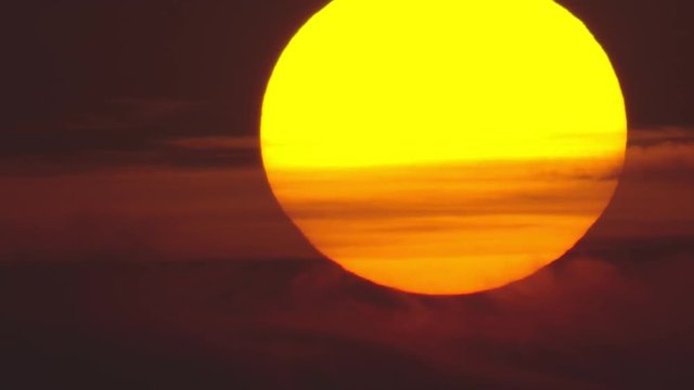 Huge orange sun with clouds, fast sunrise
