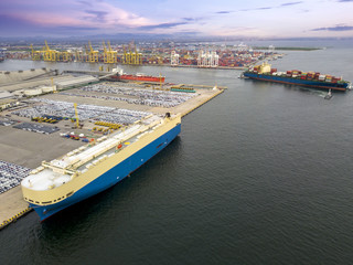 Aerial view of logistics concept commercial vehicles, cars and pickup trucks waiting to be load on to a roll-on/roll-off car carrier ship at Laem Chabang dockyard in Chonburi Province, Thailand
