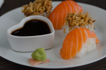 Set of sushi and rolls, wasabi, ginger and soy  with chopsticks on wooden table. Japanese food background.