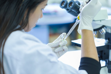 Scientist with pipette and test tube, examining samples and liquid in laboratory