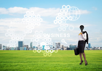 Camera headed woman standing on green grass against modern cityscape