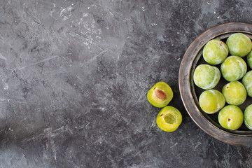 Delicious ripe green plums Greengages on ceramic black plate Black textured concrete background Autumn harvesting Flat lay Copy space