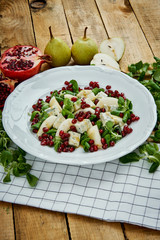 delicious salad of pear gorgonzola cheese and lettuce on a white plate on a wooden table