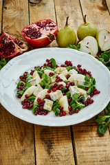 delicious salad of pear gorgonzola cheese and lettuce on a white plate on a wooden table