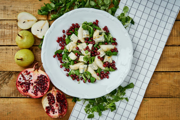 delicious salad of pear gorgonzola cheese and lettuce on a white plate on a wooden table