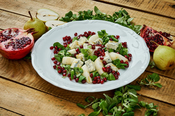 delicious salad of pear gorgonzola cheese and lettuce on a white plate on a wooden table