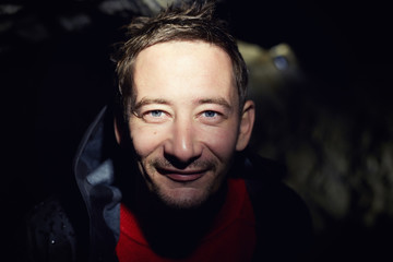 Authentic close up portrait of Caucasian male traveler, dressed in dark rain coat with drops of...