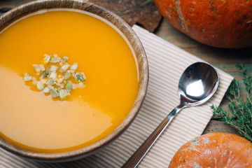 Bowl of pumpkin soup on rustic wooden background