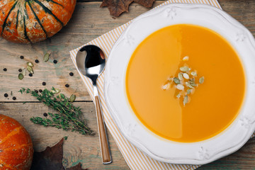 Bowl of pumpkin soup on rustic wooden background