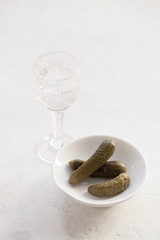 A glass of vodka and pickles on a white table