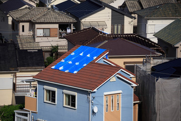Blue tarp on roof in Japanese neighborhood after damage from typhoon