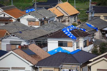 Kumatori, Japan - September 19, 2018: Blue tarps held down with sandbags on roofs damaged when...
