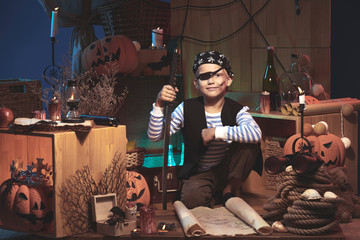 Happy boy in Halloween costume playing on decorated pirate ship