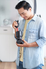 Smiling Vietnamese photographer using special tools for camera lens cleaning