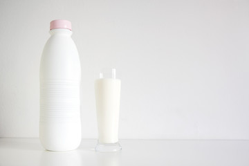 Natural fresh milk in a glass next to a bottle against a white background. Empty copy space for Editor's text.