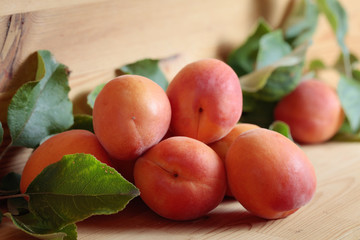 Apricots with leaves on a wooden table.