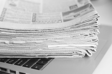 Newspapers and laptop. Pile of daily papers with news on the computer. Pages with headlines,...