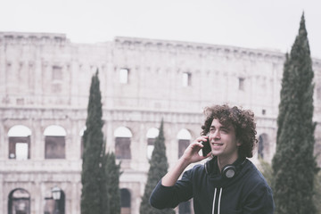 Handsome young man in sports cloths talking over his mobile phone in Rome with Colosseum in the background