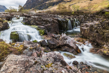 Naklejka na ściany i meble Glencoe river with smooth water flow and cloudy day. hill views at the back
