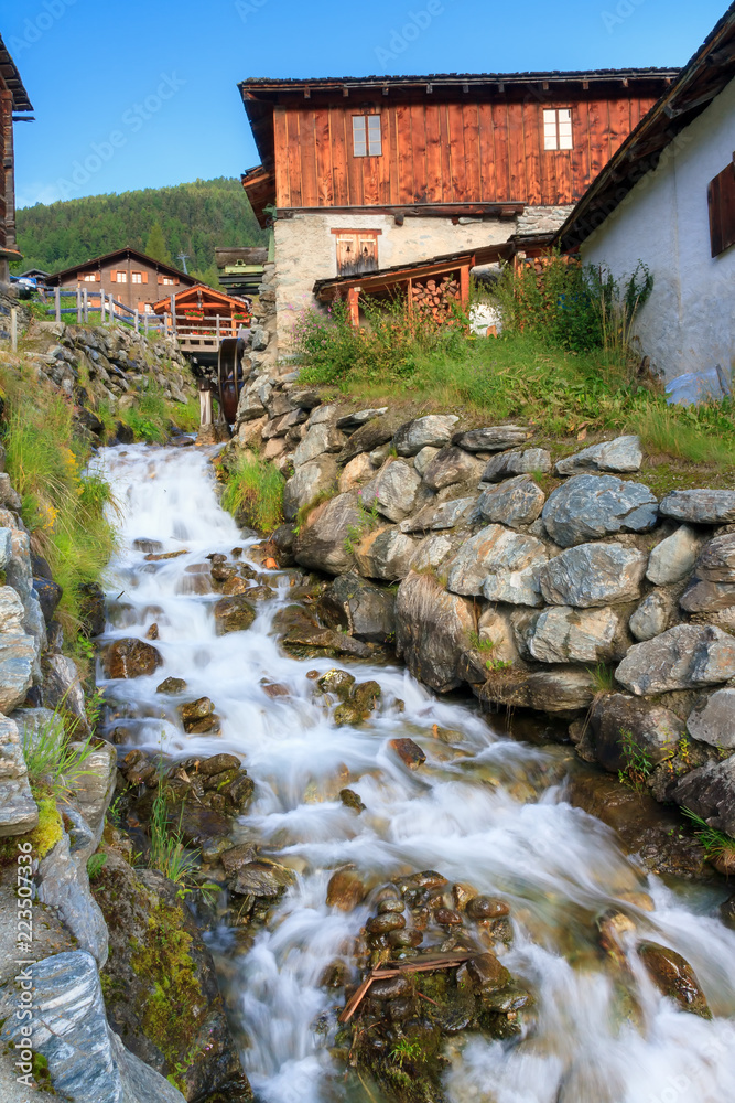 Wall mural beautiful small creek running past the ancient sawmill with water wheel in the picturesque village o