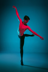 The male athletic ballet dancer performing dance on dark blue background. Studio shot. Ballet concept. Fit young man. Caucasian model