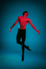 Fototapeta na wymiar The male athletic ballet dancer performing dance on dark blue background. Studio shot. Ballet concept. Fit young man. Caucasian model