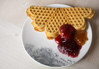 berry jam in assortment and fresh Norwegian waffles on a plate.view from above