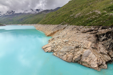 Fototapeta na wymiar Beautiful view of reservoir lake Moiry (lac de Moiry) with vibrant turquoise blue water at a low level in summer in Valais, Switzerland