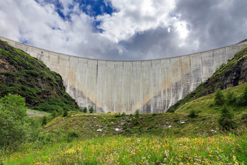 Beautiful view of the concrete dam of the reservoir lake Lac de Moiry in the alps near Grimentz, Switzerland, on a cloudy summer day
