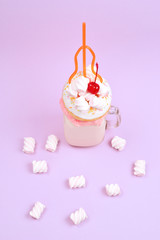 Pink strawberry freakshake with marshmallow and sweets.