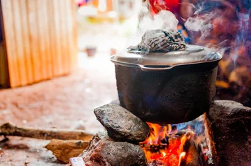 Selbstklebende Fototapeten smoking iron pot above fire in traditional african kitchen in cameroon during cooking © davide bonaldo