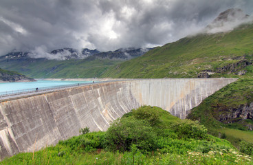 Beautiful view of the concrete dam of the reservoir lake Lac de Moiry in the alps near Grimentz, Switzerland, on a cloudy summer day
