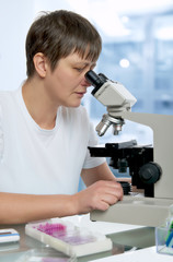 Senior female microscopist in modern laboraboty looks in the microscope