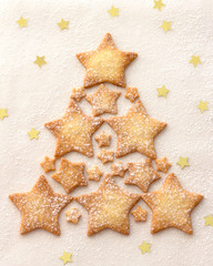 Christmas tree of a star cookie sprinkled with powdered sugar on a white background, top view