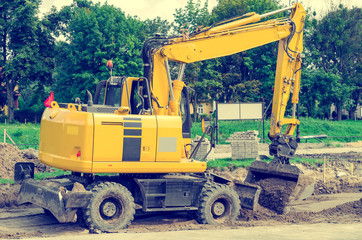 Large yellow excavator digs a hole, repairs the road, heavy equipment, road works.